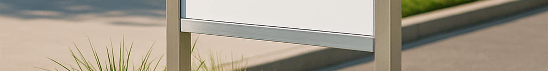 Stainless-steel monolith sign frame installed outdoors, shown as a vertical structural frame suited to concrete-set or star-picket mounting for corporate and real-estate signage.